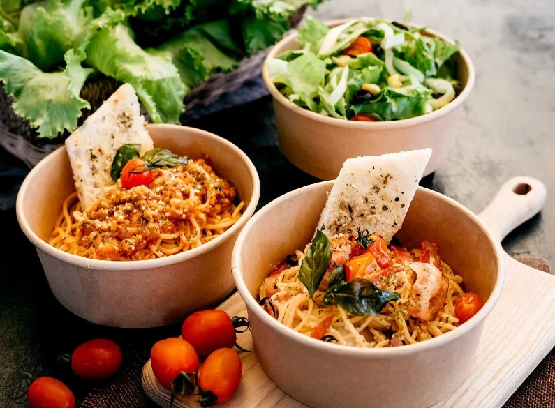 "Gourmet pasta and salad served in JC Packaging's biodegradable bowls, illustrating eco-luxury dining."