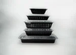 "Stack of black microwave-safe containers with clear lids, highlighting convenience and durability from www.jcpackagingdubai.com."